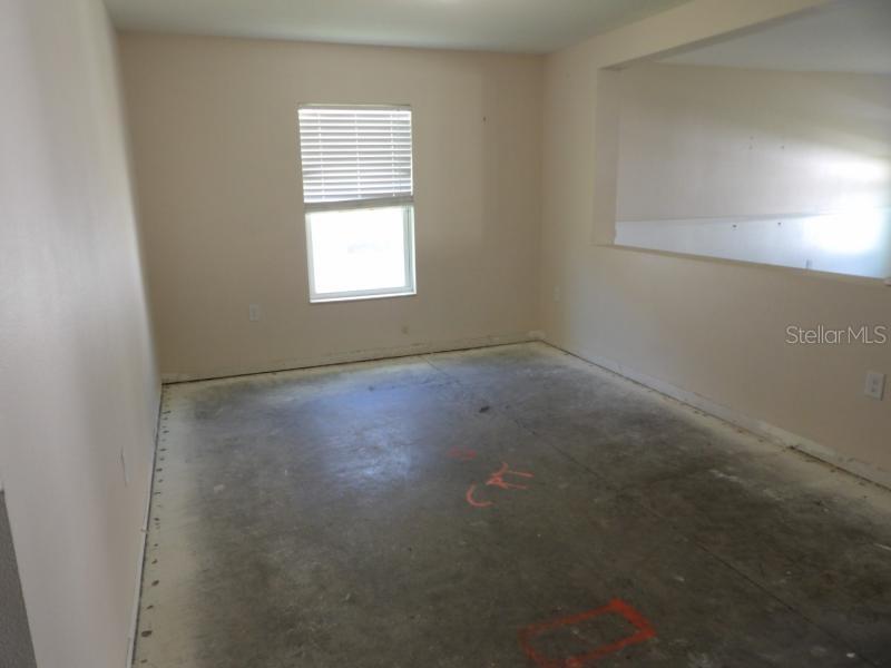 An empty room with beige walls, a single window, and an unfinished concrete subfloor — 11301 BRIGHTON KNOLL LOOP, RIVERVIEW, FL