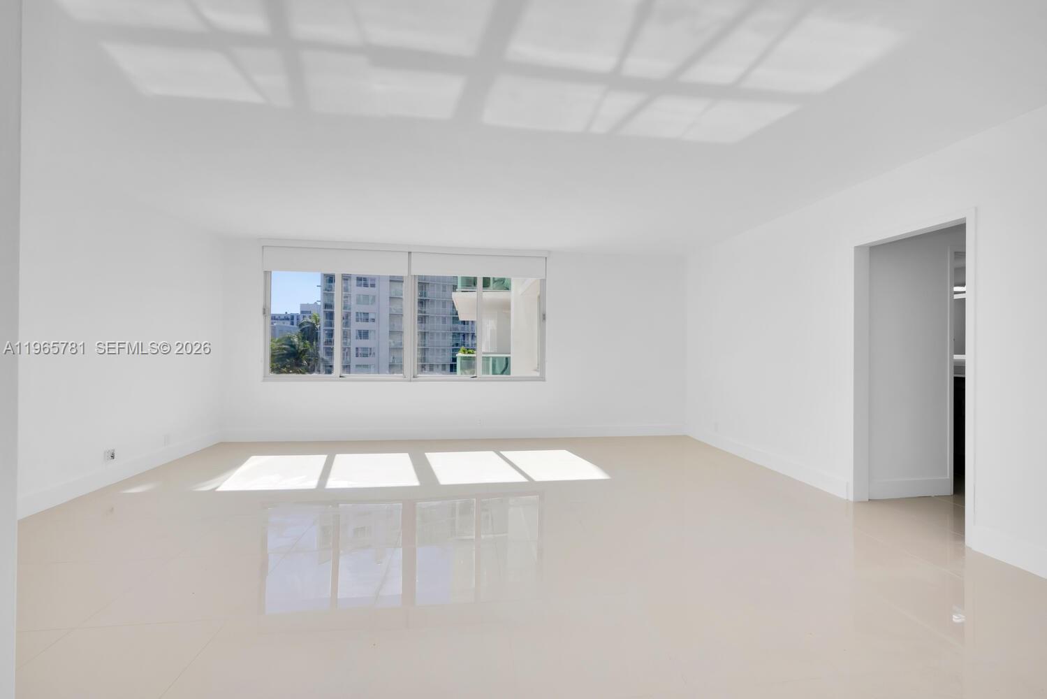 An empty room features white walls, light-colored tile flooring, and a large window — 1000 West Ave # 301, Miami Beach FL 33139, MIAMI BEACH, FL