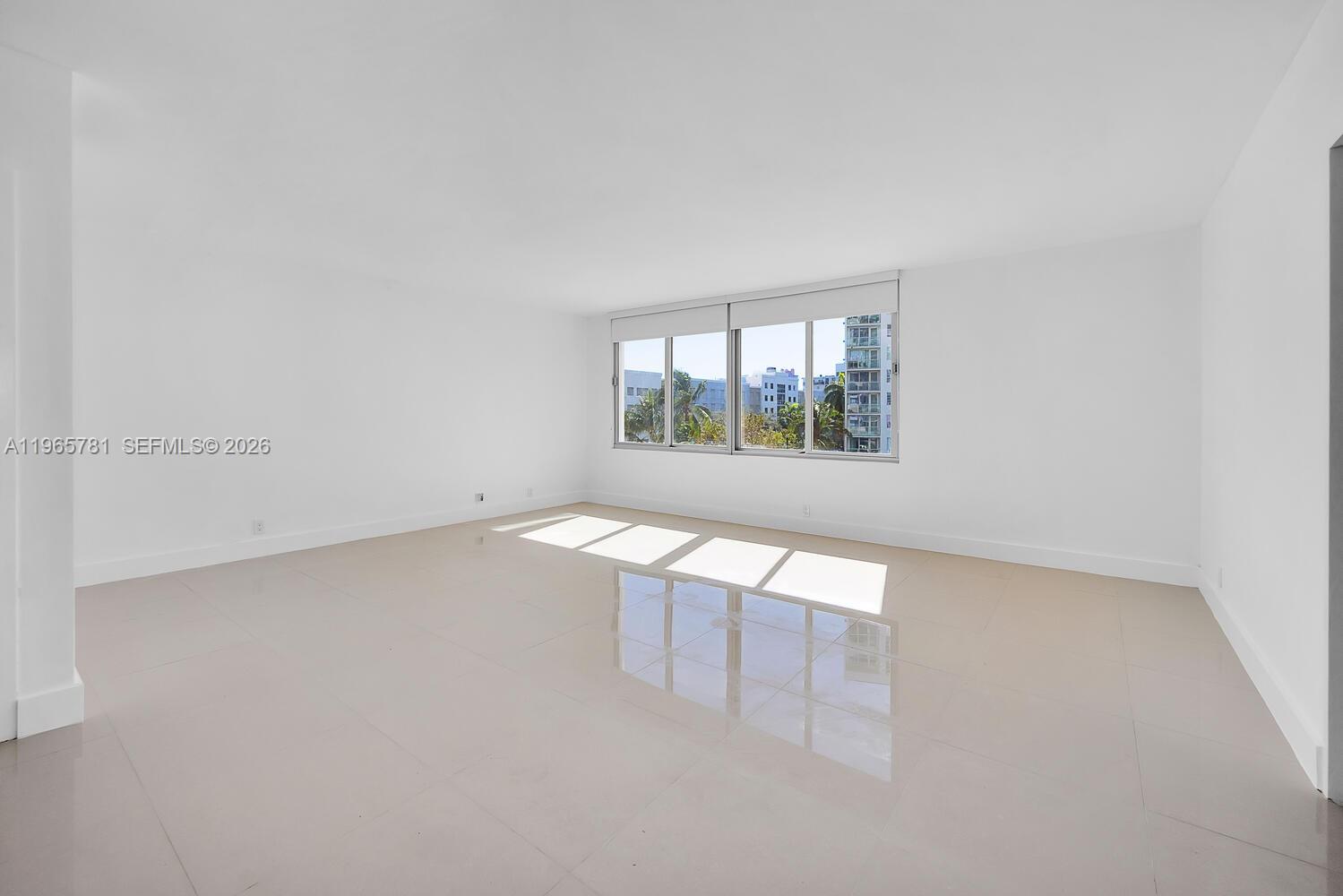 An empty room features white walls, light-colored tile flooring, and a large window — 1000 West Ave # 301, Miami Beach FL 33139, MIAMI BEACH, FL