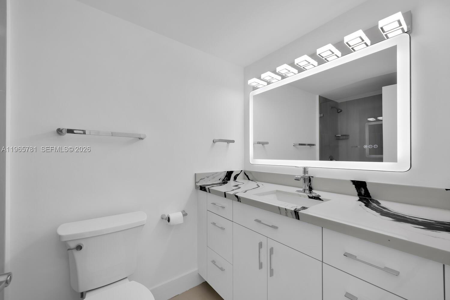 A modern bathroom features a white vanity with a black-veined marble countertop and mirror — 1000 West Ave # 301, Miami Beach FL 33139, MIAMI BEACH, FL
