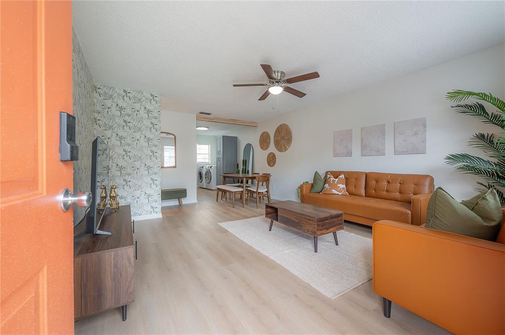 A living room with light wood flooring, a tan sofa, and a patterned accent wall — 6908 S MACDILL AVENUE UNIT A, TAMPA, FL