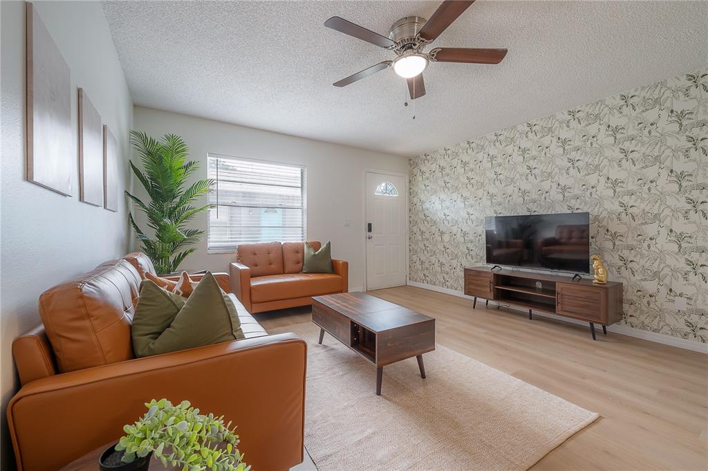 A living room features tan leather sofas, a patterned accent wall, and a ceiling fan — 6908 S MACDILL AVENUE UNIT A, TAMPA, FL