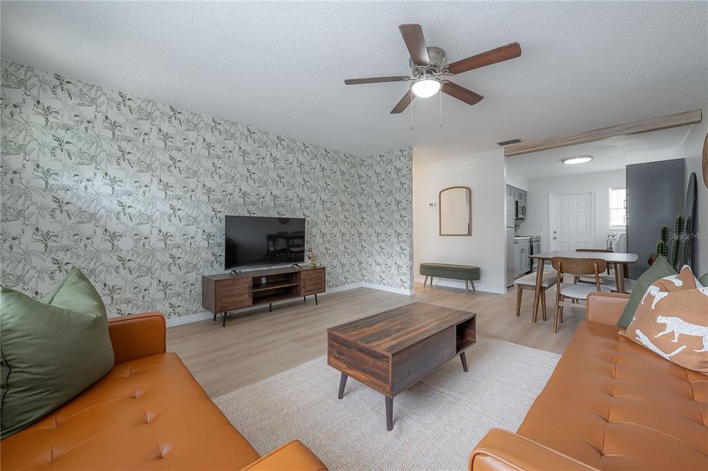 A living room features a patterned wallpaper accent wall, two leather sofas, and wood furniture — 6908 S MACDILL AVENUE UNIT A, TAMPA, FL