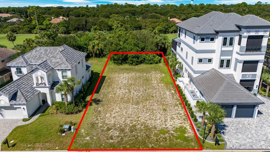 An aerial view shows a vacant rectangular lot situated between two large residential houses — 21 NORTHSHORE DRIVE, PALM COAST, FL