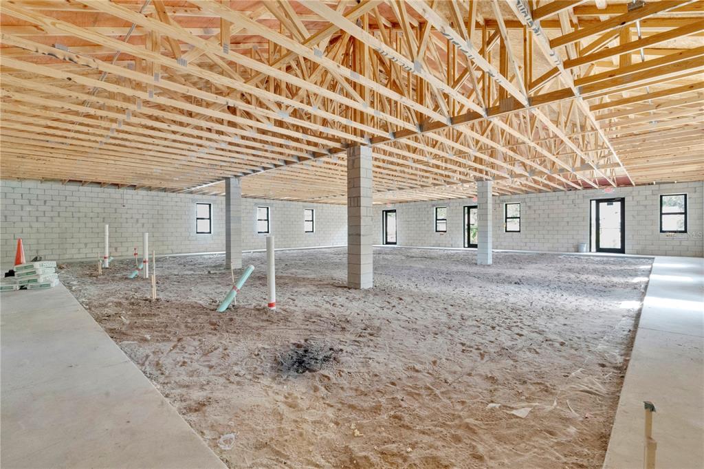 An unfinished interior space features concrete block walls, exposed wooden roof trusses, and sandy floors — 600 LEXINGTON GREEN LANE, SANFORD, FL
