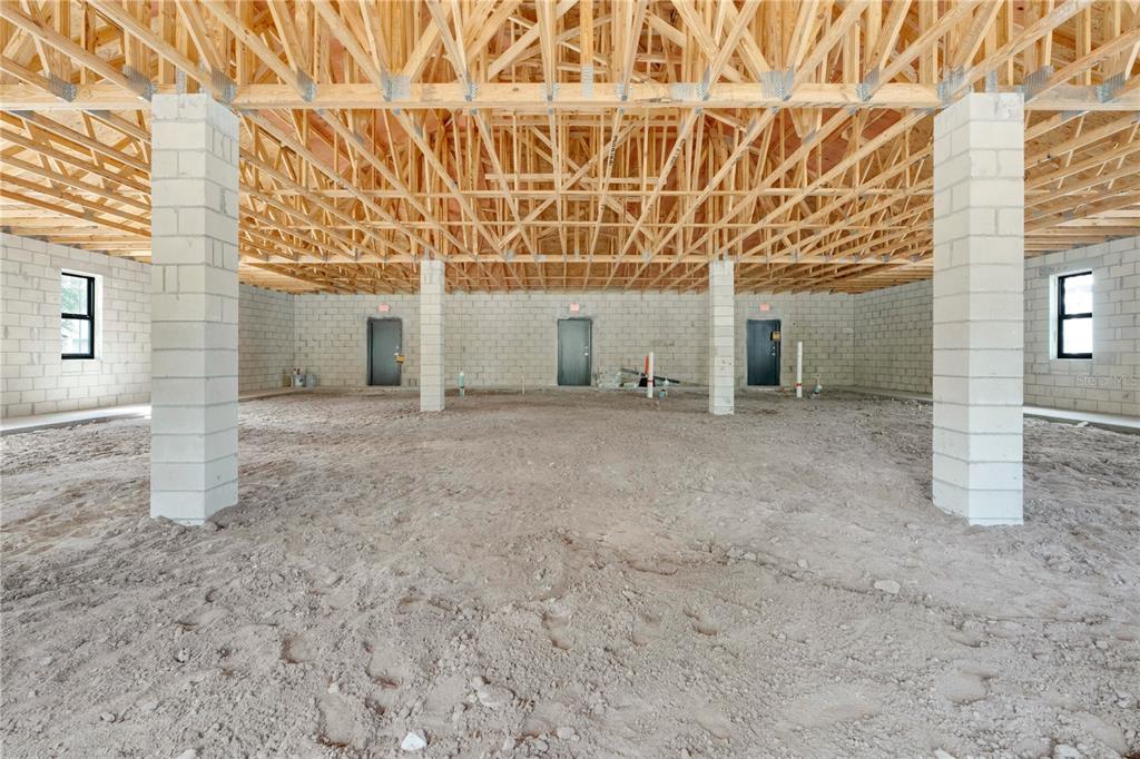 An unfinished interior space features concrete block walls, exposed wooden roof trusses, and dirt flooring — 600 LEXINGTON GREEN LANE, SANFORD, FL