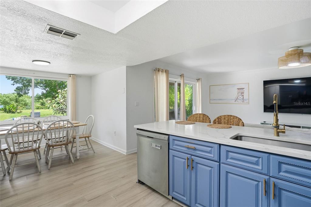 A kitchen with blue cabinets and a white island overlooks a dining area and yard — 1130 WYATT STREET, CLEARWATER, FL