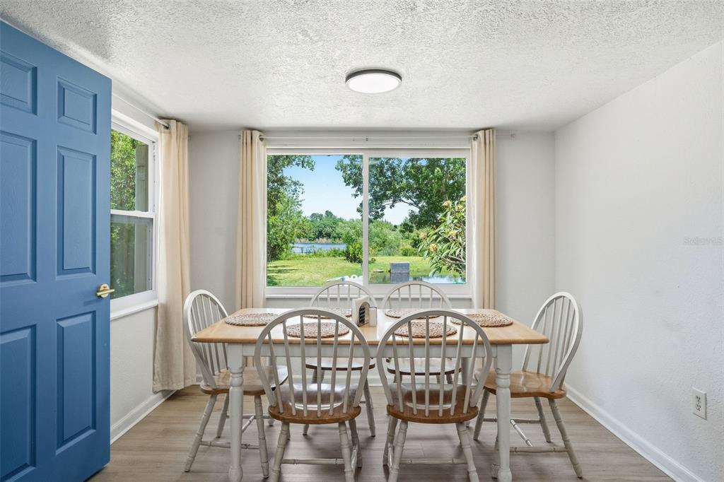 A dining room features a wooden table, six chairs, and a large window overlooking water — 1130 WYATT STREET, CLEARWATER, FL