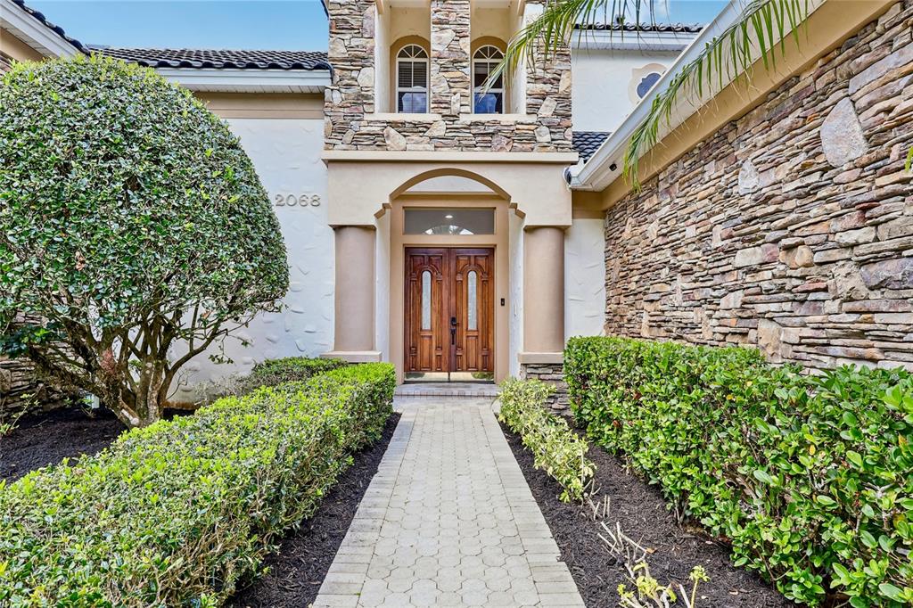 A large two-story house with a circular driveway, palm tree, and manicured landscaping — 2068 ROBERTS POINT DRIVE, WINDERMERE, FL