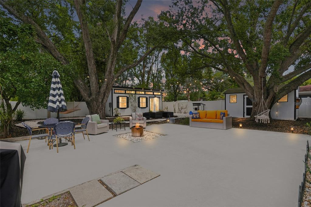 A backyard patio features a fire pit, outdoor seating, two small structures, and mature trees — 3305 W BALLAST POINT BOULEVARD, TAMPA, FL