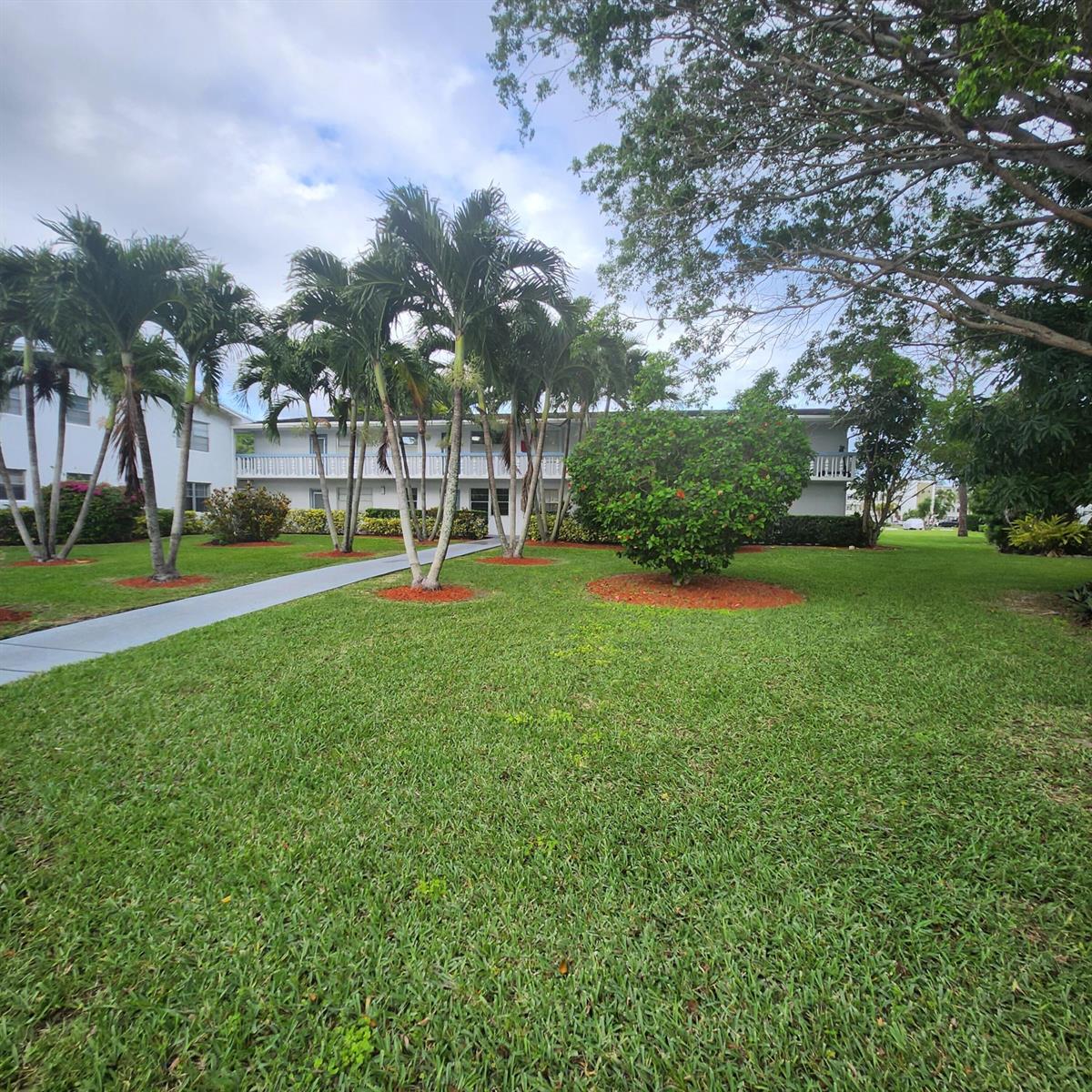 A multi-story apartment building with a walkway, palm trees, and a lawn in front — 643 Durham W, Deerfield Beach FL 33442, DEERFIELD BEACH, FL