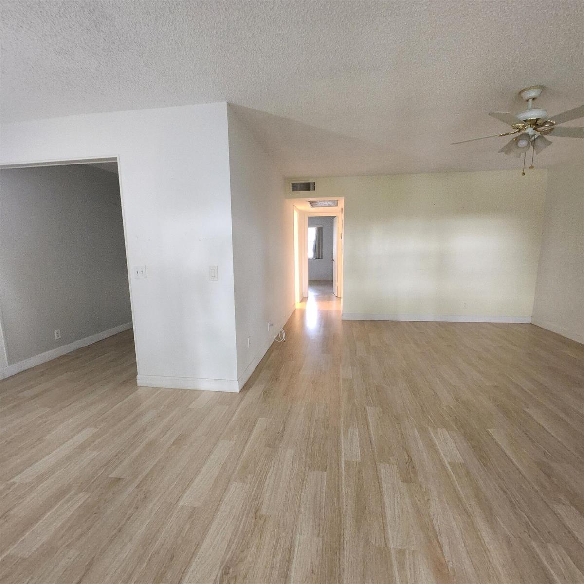 An empty room with light wood-look flooring, white walls, and a ceiling fan — 643 Durham W, Deerfield Beach FL 33442, DEERFIELD BEACH, FL