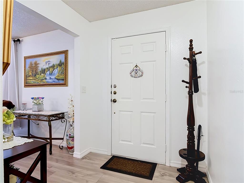 An entryway features a white door, a wooden coat rack, and a console table nearby — 1535 LAVILLA STREET, DELTONA, FL