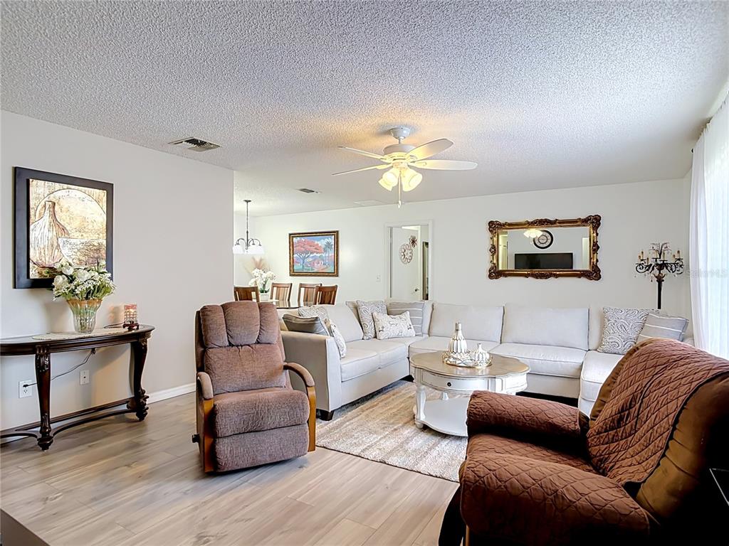 A living room features light wood-look flooring, a sectional sofa, and two brown recliners — 1535 LAVILLA STREET, DELTONA, FL