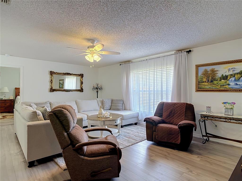 A living room features a sectional sofa, two recliners, a ceiling fan, and wood-look flooring — 1535 LAVILLA STREET, DELTONA, FL