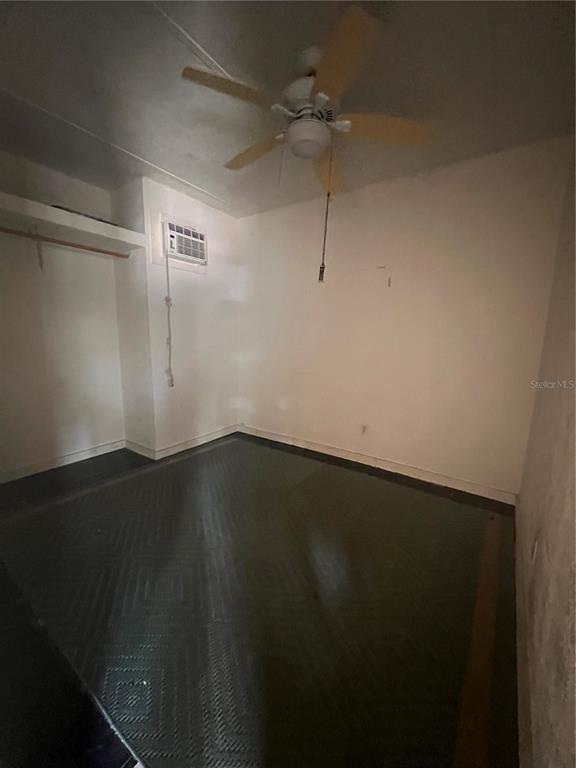 An empty bedroom features a ceiling fan, a wall-mounted air conditioner, and dark flooring — 3029 FORSYTH ROAD, WINTER PARK, FL