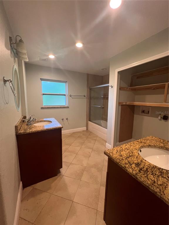 A bathroom with two granite-topped vanities, a tiled floor, and a shower-tub combination — 3029 FORSYTH ROAD, WINTER PARK, FL