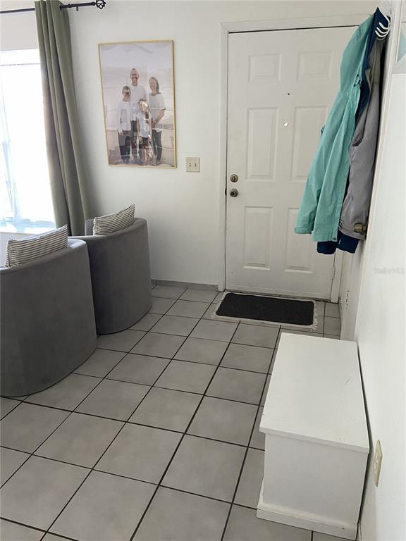 This entryway features tiled flooring, two gray armchairs, a white storage bench, and a door — 3133 QUAIL DR, DELTONA, FL