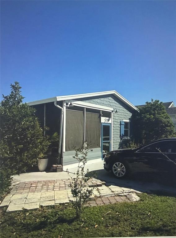 A blue house with a screened-in porch and a brick patio sits beside a car — 50989 HIGHWAY 27 UNIT 210, DAVENPORT, FL