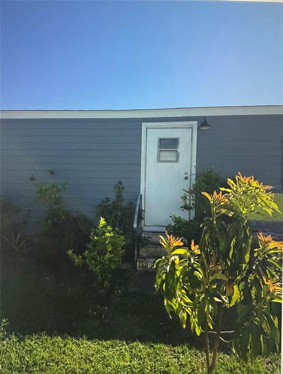 A white door with a small window is centered on the blue-sided exterior wall — 50989 HIGHWAY 27 UNIT 210, DAVENPORT, FL