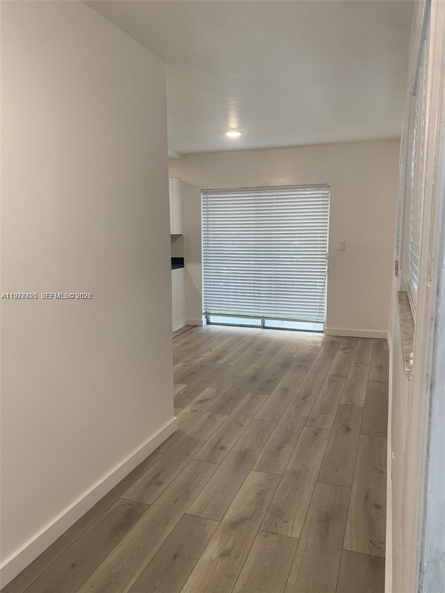 A room with light-colored walls, wood-look flooring, and a sliding glass door with blinds — 8295 NE Miami Ct # 1, Miami FL 33138, MIAMI, FL
