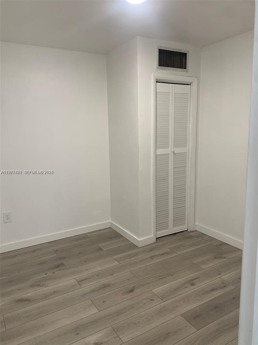 A small room features white walls, light wood-look flooring, and a white louvered closet door — 8295 NE Miami Ct # 1, Miami FL 33138, MIAMI, FL