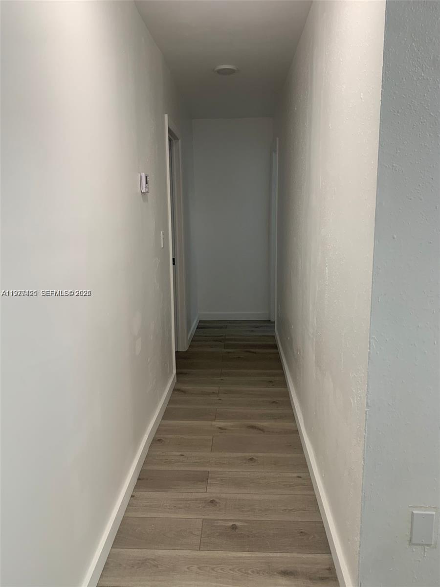 A narrow hallway features light wood-look flooring and white walls with two doorways — 8295 NE Miami Ct # 1, Miami FL 33138, MIAMI, FL