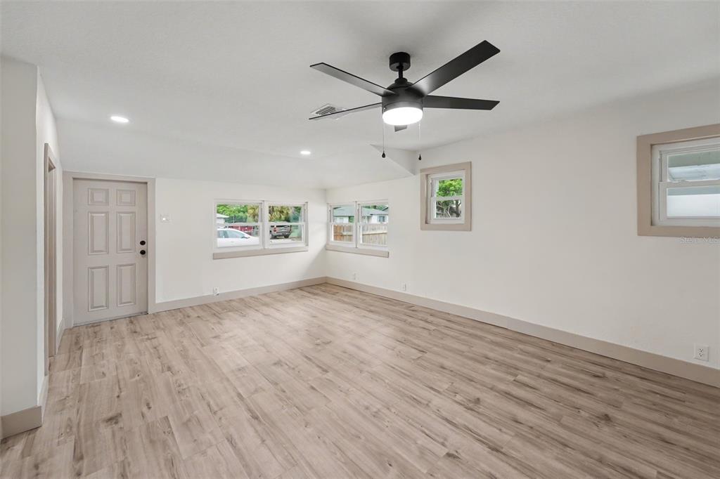 An empty room with light wood-look flooring, white walls, a ceiling fan, and several windows — 2850 59TH AVENUE N, ST PETERSBURG, FL