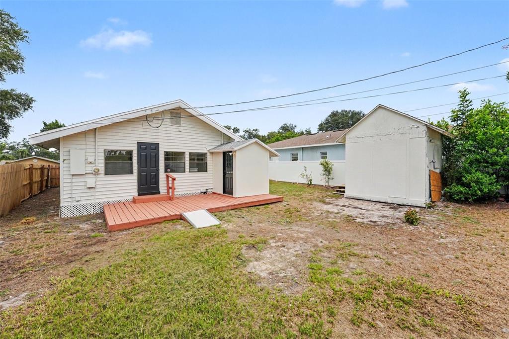 The exterior of a house features white siding, a red wooden deck, and a shed — 2850 59TH AVENUE N, ST PETERSBURG, FL