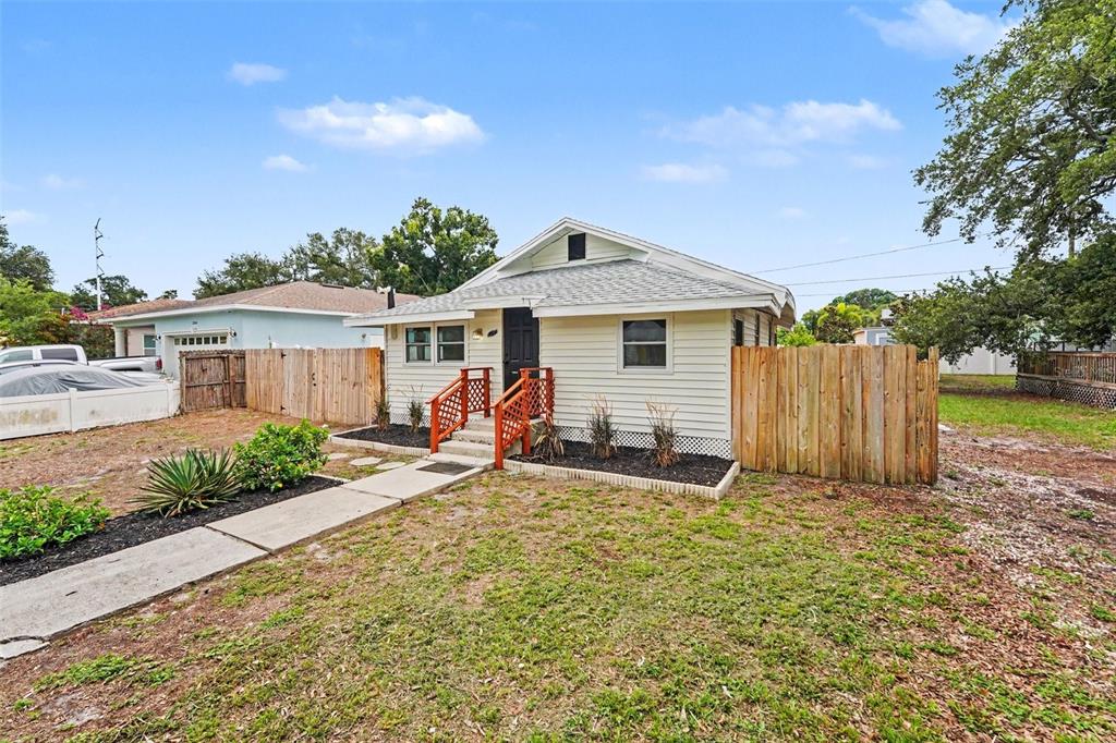 A small, light-colored house with a front porch, wooden railings, and a wooden fence — 2850 59TH AVENUE N, ST PETERSBURG, FL