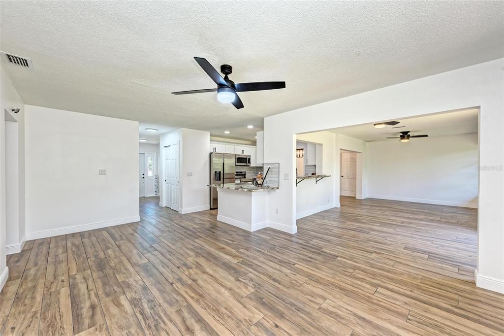 An open-concept living area features wood-look tile flooring, a kitchen island, and a ceiling fan — 3120 GUADALUPE DRIVE, PUNTA GORDA, FL