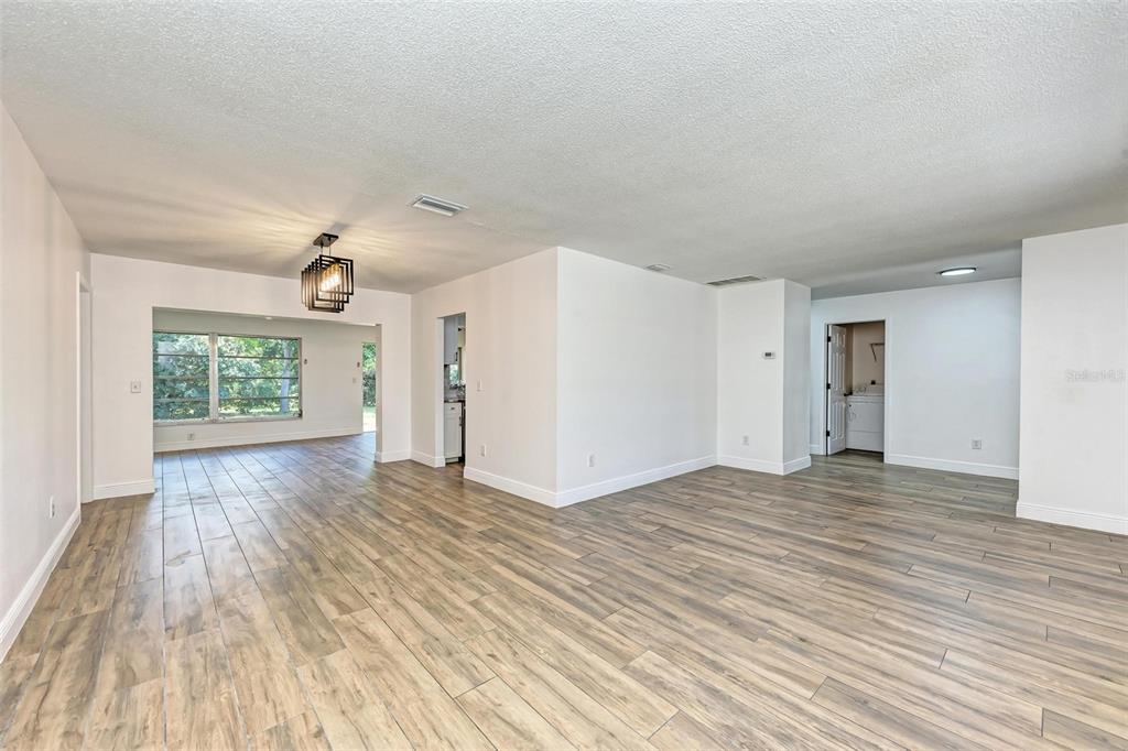 An open-concept living area features light wood-look tile flooring, white walls, and a modern chandelier — 3120 GUADALUPE DRIVE, PUNTA GORDA, FL