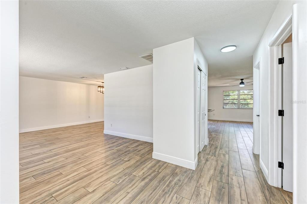 An interior view shows a hallway with wood-look tile flooring leading to a living area — 3120 GUADALUPE DRIVE, PUNTA GORDA, FL