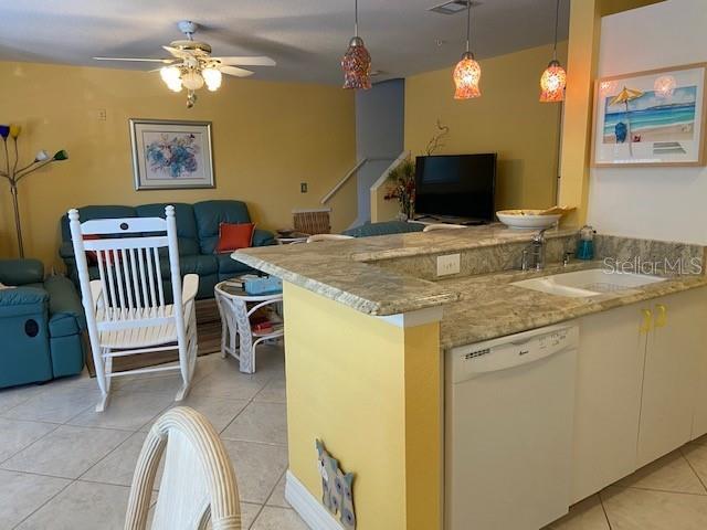 A living room and kitchen area with yellow walls, tile floors, and a granite countertop — 850 S TAMIAMI TRAIL UNIT 130, SARASOTA, FL