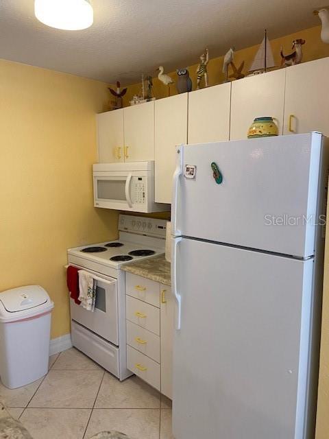 A kitchen features white appliances, yellow walls, and decorative figurines displayed above the cabinets — 850 S TAMIAMI TRAIL UNIT 130, SARASOTA, FL