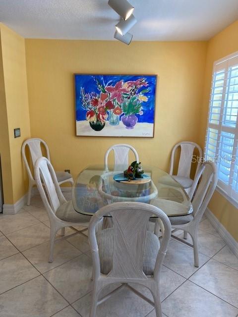 A dining room features a glass-topped table, four white chairs, and a colorful floral painting — 850 S TAMIAMI TRAIL UNIT 130, SARASOTA, FL