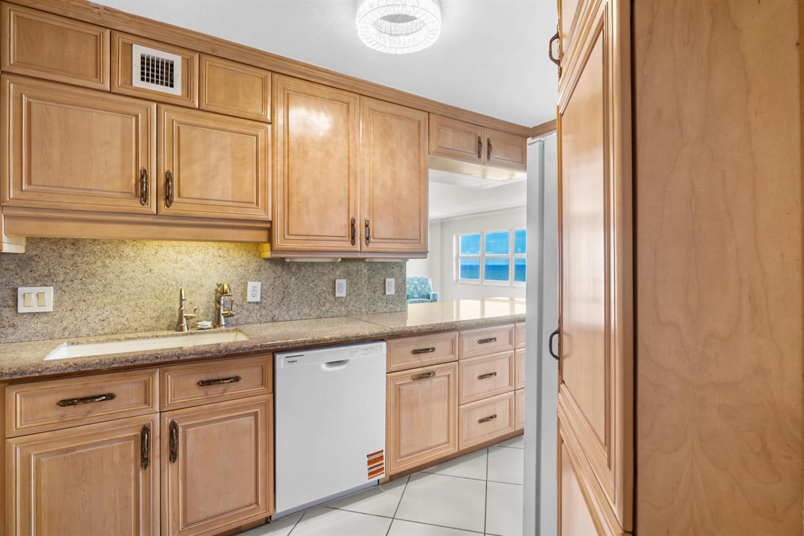 A kitchen with light wood cabinets, granite countertops, a white dishwasher, and tiled floors — 111 N Pompano Beach Boulevard # 1609, Pompano Beach FL 33062, POMPANO BEACH, FL