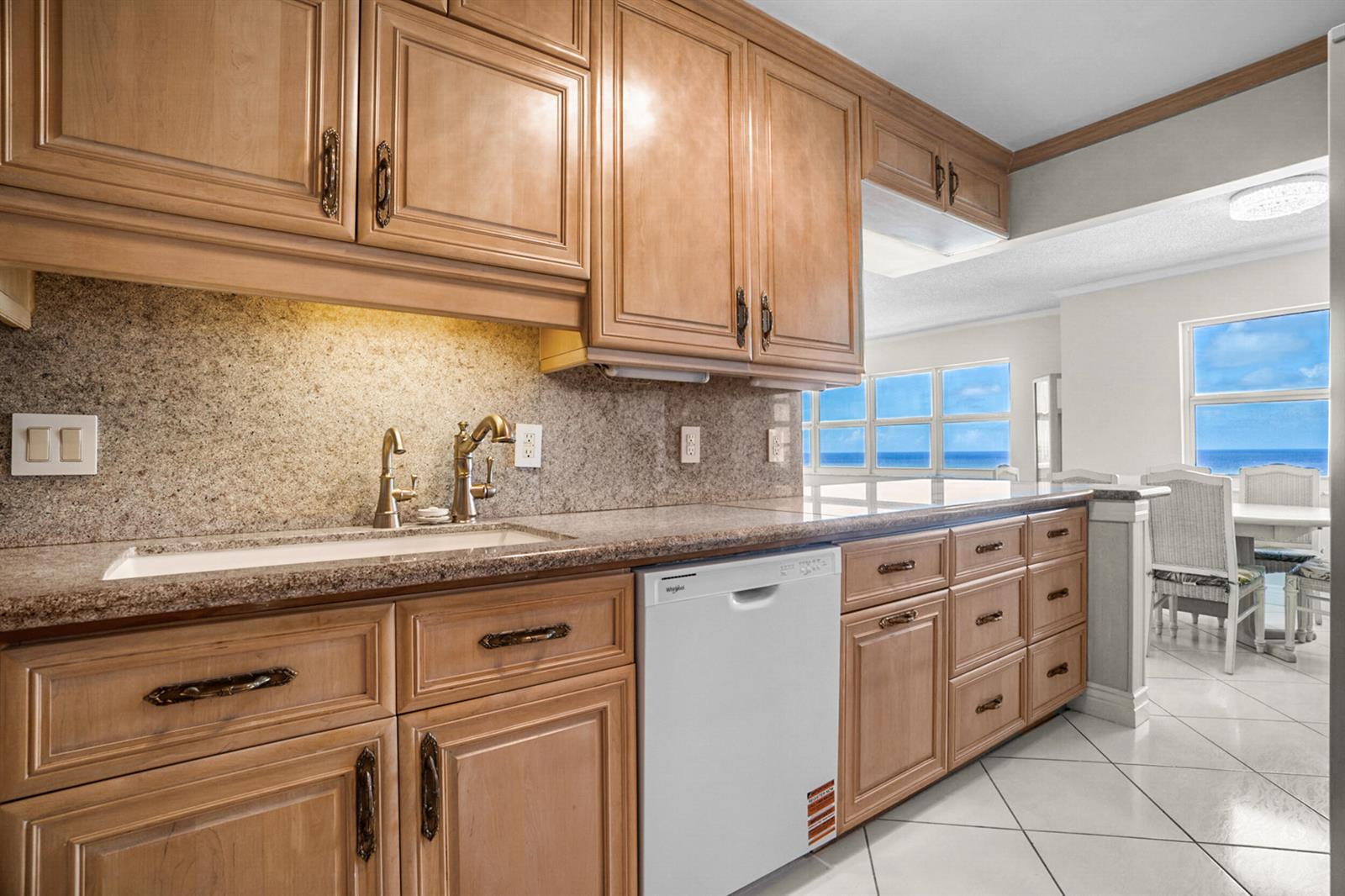 A kitchen with wood cabinets, granite countertops, a white dishwasher, and a view of the ocean — 111 N Pompano Beach Boulevard # 1609, Pompano Beach FL 33062, POMPANO BEACH, FL