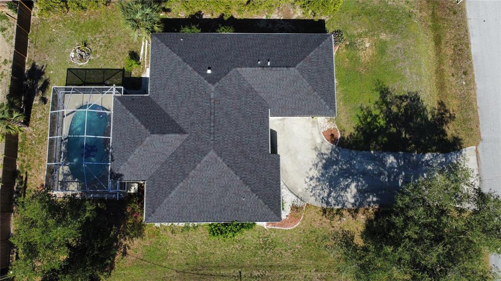 An aerial view of a house with a shingled roof, pool enclosure, and concrete driveway — 21498 BEAVERTON AVENUE, PORT CHARLOTTE, FL