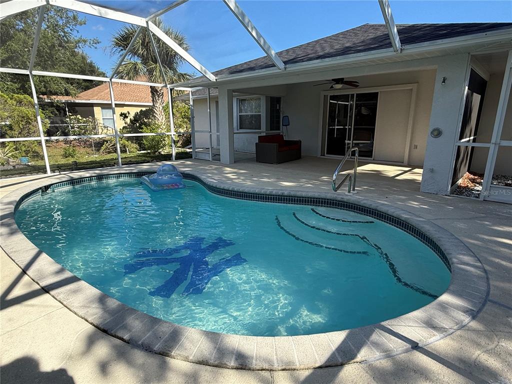 A screened-in patio features a swimming pool with a New York Yankees logo inlay — 21498 BEAVERTON AVENUE, PORT CHARLOTTE, FL