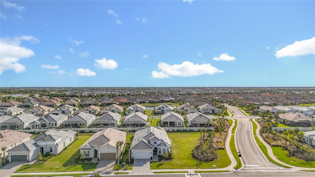 An aerial view shows a suburban neighborhood with single-family homes, paved streets, and green lawns — 16306 ISOLA PL, LAKEWOOD RANCH, FL