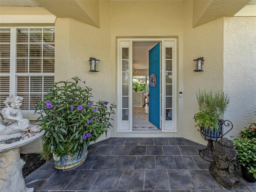 A front entryway features a blue door, tiled porch, and potted plants — 905 BRAMLEY COURT UNIT 9, VENICE, FL