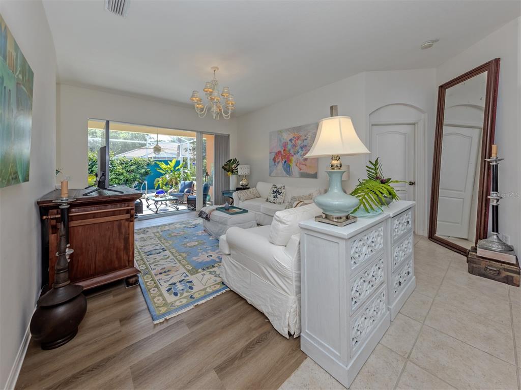 A living room features white sofas, a blue patterned rug, and a large floor mirror — 905 BRAMLEY COURT UNIT 9, VENICE, FL