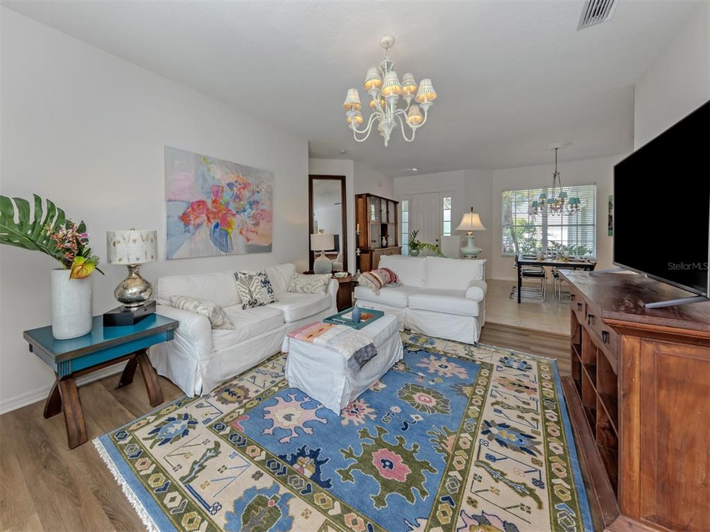 A living room features white sofas, a patterned blue rug, and a wooden media console — 905 BRAMLEY COURT UNIT 9, VENICE, FL