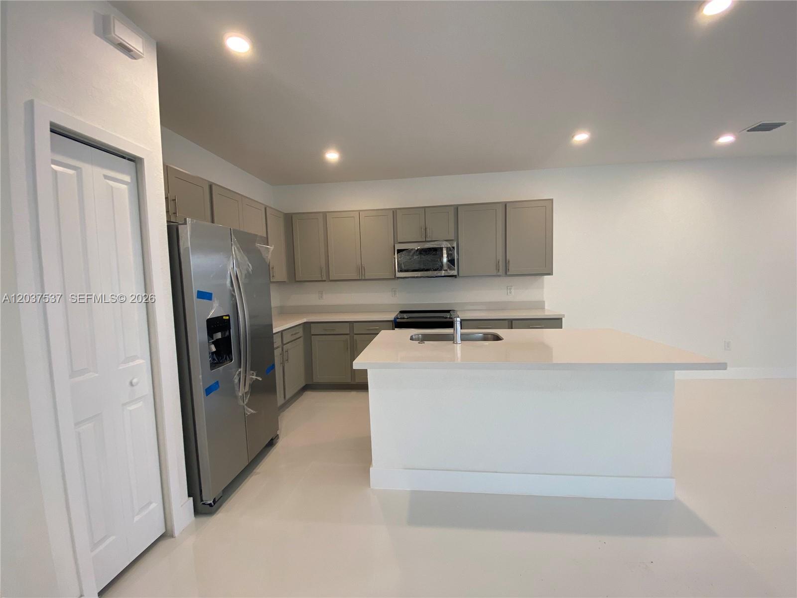A modern kitchen features gray cabinets, stainless steel appliances, and a white quartz island — 2402 SW 145th Pl # 0, Miami FL 33175, MIAMI, FL
