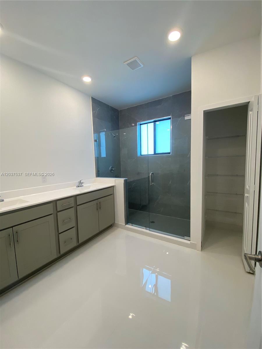 A bathroom features a double vanity with gray cabinets, a glass-enclosed shower, and white flooring — 2402 SW 145th Pl # 0, Miami FL 33175, MIAMI, FL