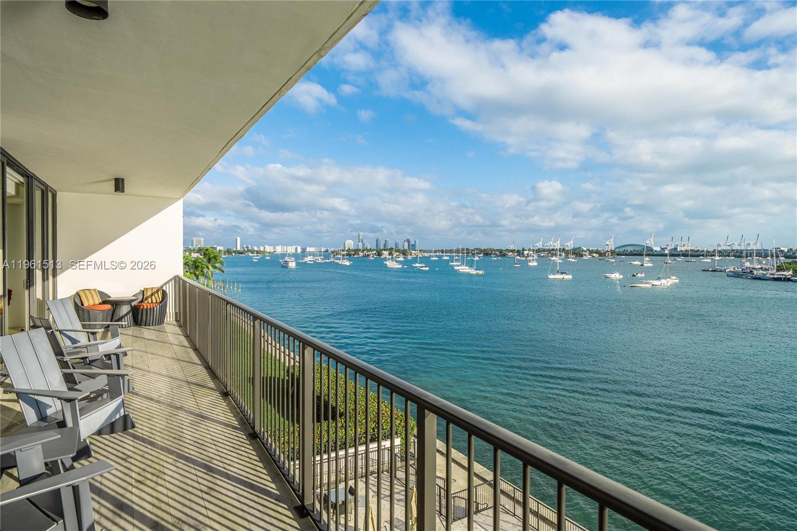 A balcony with gray chairs overlooks a bay filled with numerous anchored sailboats — 1000 Venetian Way # 403, Miami Beach FL 33139, MIAMI BEACH, FL