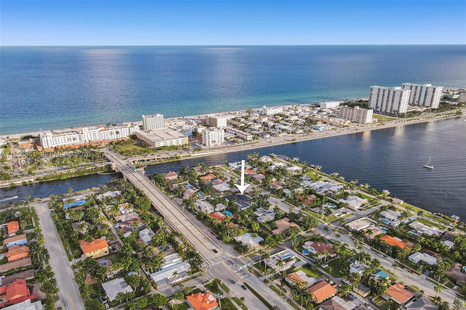 An aerial view shows a residential neighborhood with a white arrow pointing to a house — 725 Harrison St, Hollywood FL 33019, HOLLYWOOD, FL