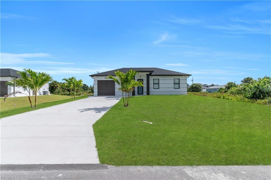 A single-story house with a gray exterior, dark roof, and a concrete driveway — 713 ROMA AVENUE S, LEHIGH ACRES, FL