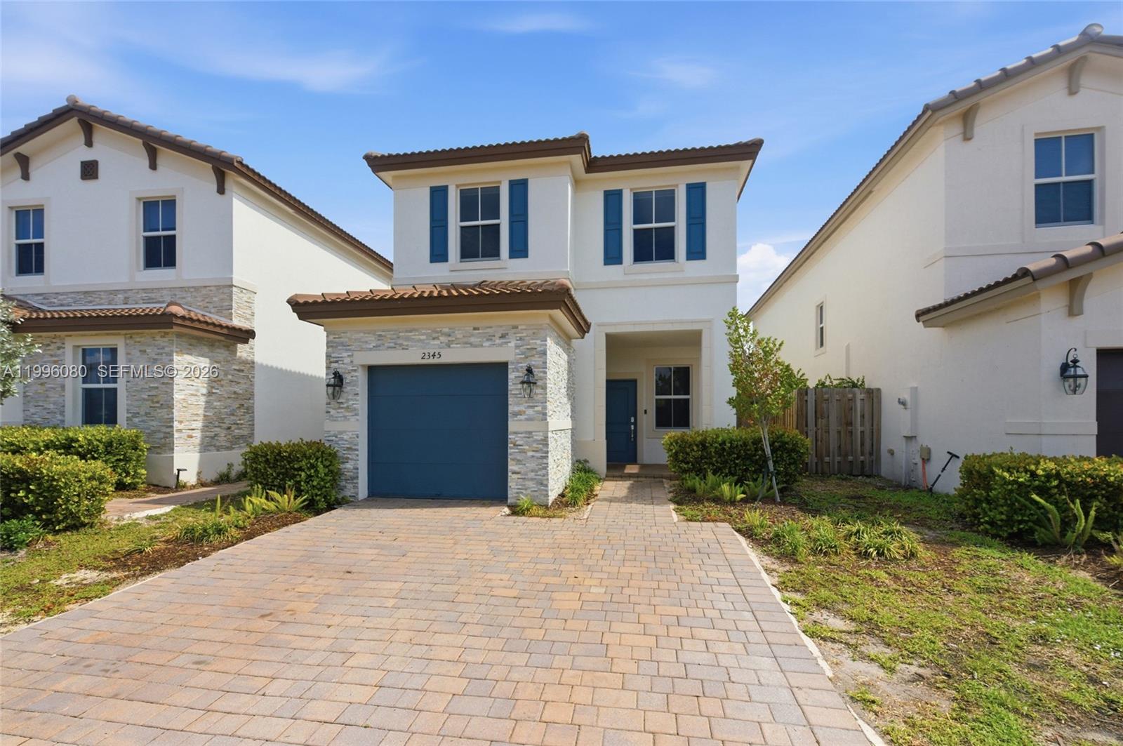 A two-story house with a stone-accented garage, blue shutters, and a paved driveway — 2345 NW 131st Cir # 2345, Miami FL 33167, MIAMI, FL